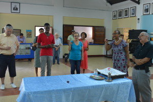 a handful of congregants and visitors hold glasses of kosher wine and sing, in the cultural heritage center of Jamaica's last synagogue, the Sha’are Shalom.