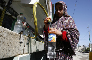 A Palestinian girl fills a bottle with fresh water. (Abed Rahim Khatib/ FLASH90)
