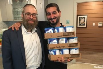 Rabbi Chaim Lazaroff, left, Chabad, hands containers of baby formula to a father in Houston.