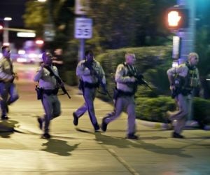 Police run to cover at the scene of the shooting. (AP Photo/John Locher)