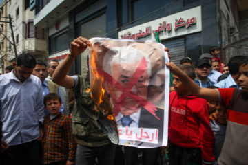 Palestinians burn a poster of Mahmoud Abbas. (Abed Rahim Khatib/Flash90)