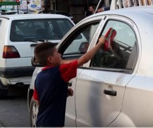 Orphan washes car window in Mosul, Iraq