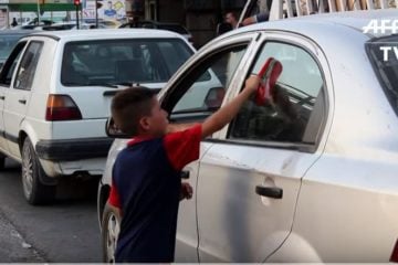 Orphan washes car window in Mosul, Iraq