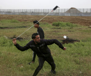 A rioter hurls stones at Israelis at the Gaza Strip border. (AP Photo/Adel Hana)