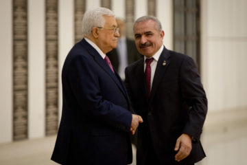 Mohammad Ishtayeh, right, shakes hands with Mahmoud Abbas. (AP Photo/Majdi Mohammed)