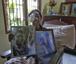 Sri Lankan Anusha Kumari holds portraits of daughter and son. (AP Photo/Gemunu Amarasinghe)