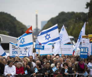 People with Israeli flags and banners, reading 'never again' , right, attend a rally against anti-Semitism near the Brandenburg Gate in Berlin.