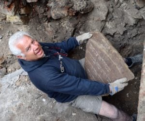 Member of the excavating team holding one of the inscription remnants from the Vilnius synagogue .