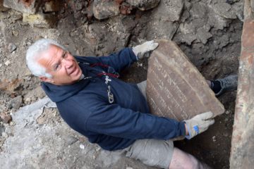 Member of the excavating team holding one of the inscription remnants from the Vilnius synagogue .