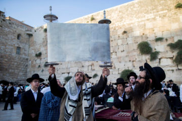 Raising a Torah scroll as part of prayers for the Fast of the 17th of Tammuz at the Western Wall