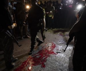 Hamas masked gunmen stand guard around blood on the ground after an explosion targeted a Hamas police checkpoint in Gaza City, Tuesday, Aug. 27, 2019.
