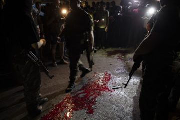 Hamas masked gunmen stand guard around blood on the ground after an explosion targeted a Hamas police checkpoint in Gaza City, Tuesday, Aug. 27, 2019.