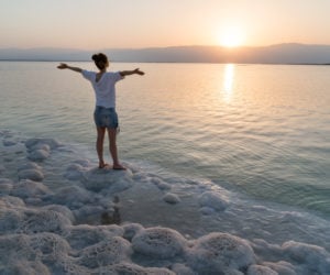 Girl meets sunrise on the shore of the Dead Sea in Israel