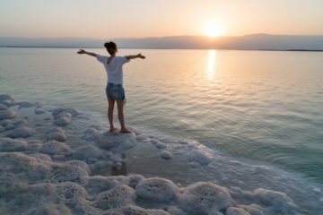 Girl meets sunrise on the shore of the Dead Sea in Israel