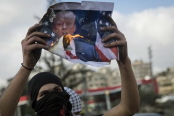 Palestinian protesters burn a poster with a picture of U.S. President Donald Trump