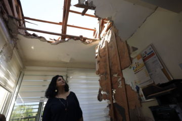 A woman looks at the damage to a house in Sderot