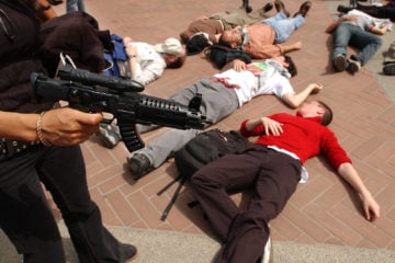A protester holding a plastic gun stands over other demonstators with the group "Students for Justice in Palestine," during a mock "die-in" on Wednesday, April 9, 2003, on the University of California at Berkeley campus in Berkeley, Calif.