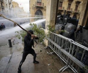 Anti-government demonstrators clash with riot police at a road leading to the parliament building in Beirut, Lebanon, Saturday, Jan. 18, 2020.