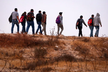 Palestinians illegally crossing the Israeli security fence through a hole to enter Israel.