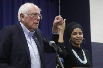 Former Democratic presidential candidate Sen. Bernie Sanders, D-Vt., and Rep. Ilhan Omar, D-Minn., clasp hands after she introduced him at a campaign event, Friday, Dec. 13, 2019, in Manchester, New Hampshire. (AP Photo/Elise Amendola)