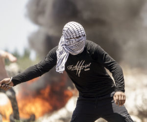 Palestinian throwing rocks at Israeli soldiers