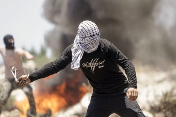 Palestinian throwing rocks at Israeli soldiers