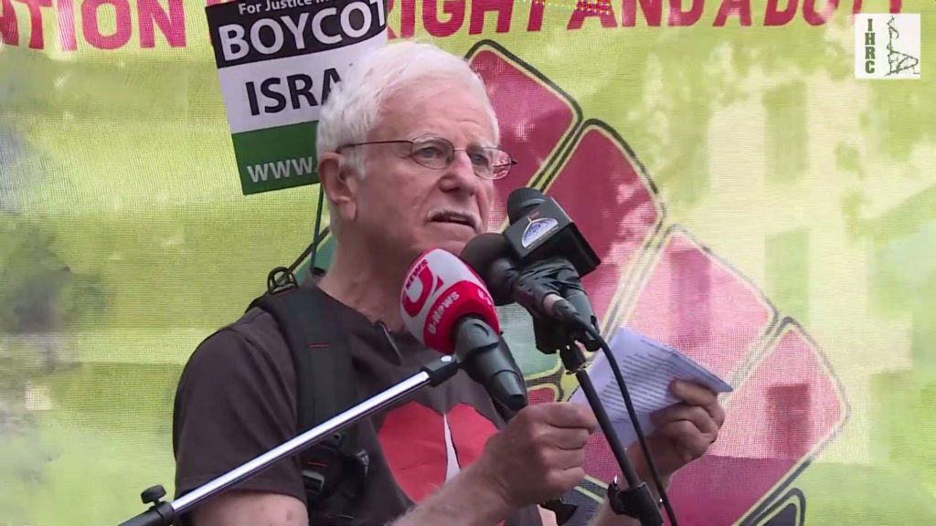 Prof. Haim Bresheeth wearing a "boycott Israel" flag
