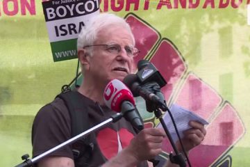 Prof. Haim Bresheeth wearing a "boycott Israel" flag