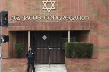 A security guard stands at the entrance of the Etz Jacob Congregation/Ohel Chana High School building Friday, Feb. 15, 2019, in Los Angeles. (AP Photo/Marcio Jose Sanchez)