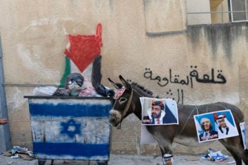 A Palestinian child stands near a donkey with pictures depicting Abu Dhabi Crown Prince Mohammed bin Zayed al-Nahyan and Foreign Minister Abdullah bin Zayed and Israeli Prime Minister Benjamin Netanyahu during a protest against normalizing ties with Israel, in the West Bank village of Kafr Qaddum near the West Bank city of Nablus, Friday, Sept. 18, 2020. (AP Photo/Majdi Mohammed)