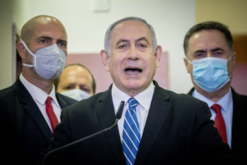 Israeli prime minister Benjamin Netanyahu is surrounded by Likud lawmakers as he gives a press statement ahead of the start of his trial at the District Court in Jerusalem on May 24, 2020. (Flash90/Yonatan Sindel)