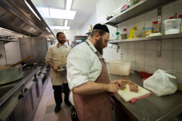 A Jewish man cooks inside the Kosher restaurant Hoffy's in Antwerp, Belgium on August 07, 2014. (Flash90/Johanna Geron)