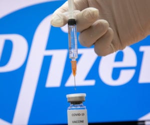 A photo illustration of a syringe and and a bottle reading "Covid-19 Vaccine" next to the Pfizer company logo in Jerusalem on December 10, 2020. (Flash90/Olivier Fitoussi)