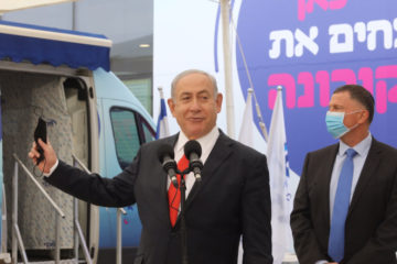 Israeli Prime Minister Benjamin Netanyahu and Health Minister Yuli Edelstein attend a press conference at a Maccabi vaccine center in Tel aviv on December 13 2020. (POOL/Marc Israel Sellem)