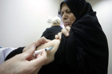 Palestinian medical workers inject pilgrims with the H1N1 flu vaccine