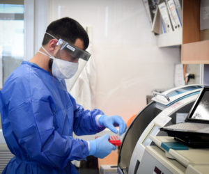 A medical worker in Barzilay hospital, in the southern Israeli city of Ashkelon, wears protective gear, as he handles a Coronavirus test sample on March 29, 2020. (Flash90)