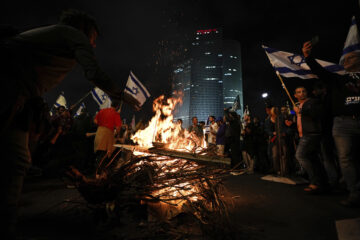 Demonstrators set up bonfires and block a highway during a protest against plans by Prime Minister Benjamin Netanyahu's government to overhaul the judicial system in Tel Aviv, Israel, Saturday, March 25, 2023. (AP Photo/Ariel Schalit)