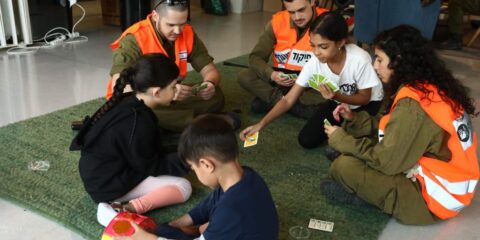 Displaced Israelis playing cards on the ground.